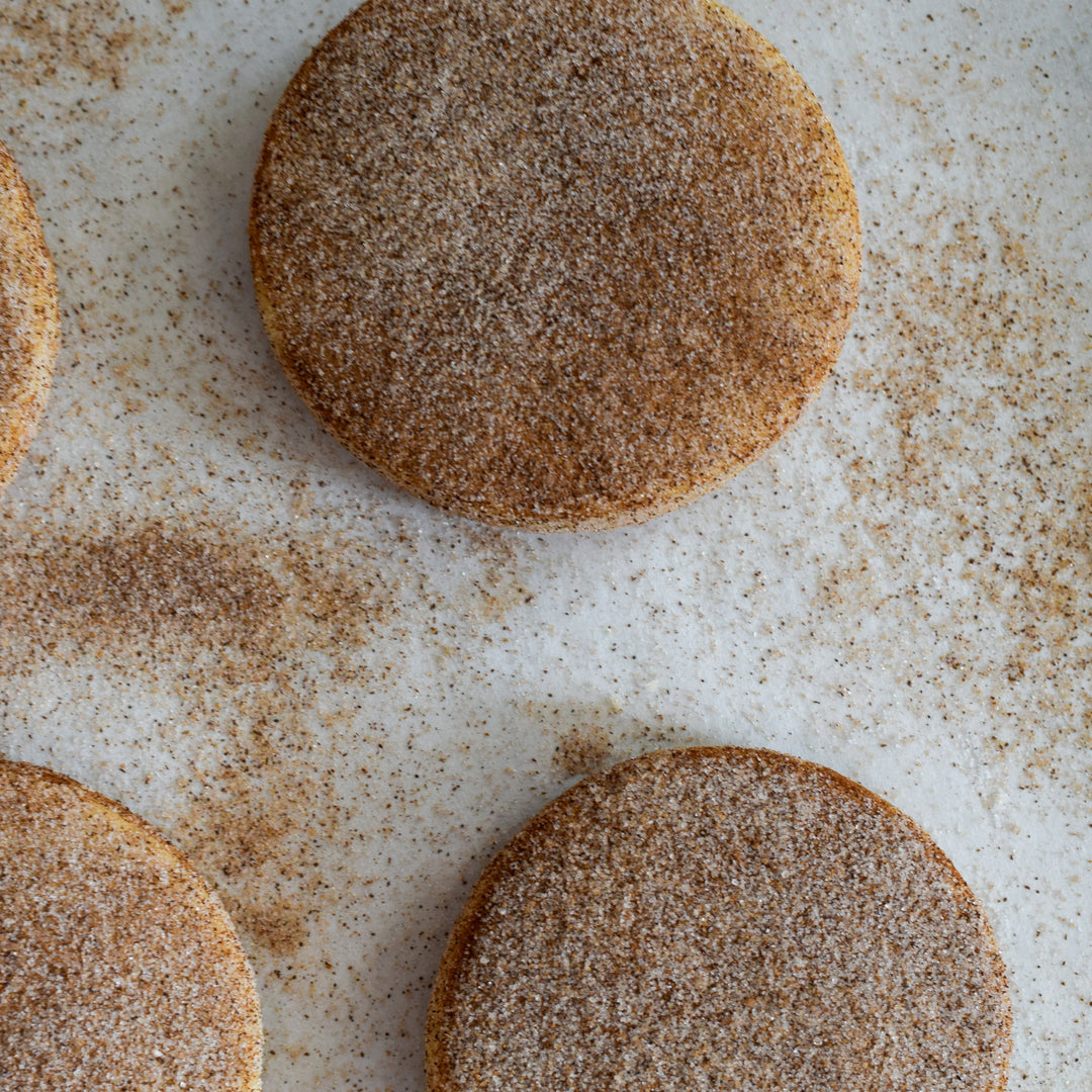 Three cinnamon shortbread cookies with a dusting of cinnamon sugar, on a white background.