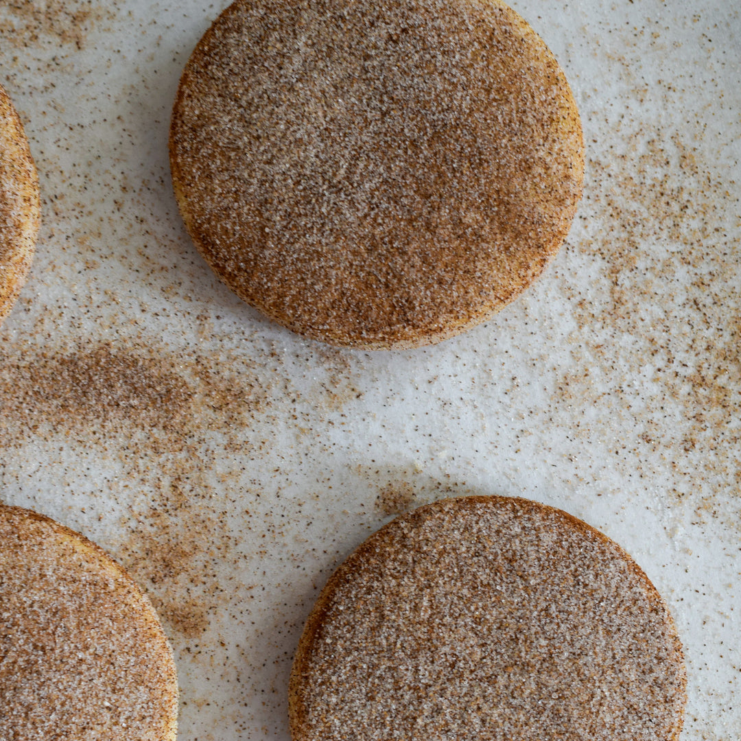 Three gluten free cinnamon shortbread cookies with a dusting of cinnamon sugar, on a white background.